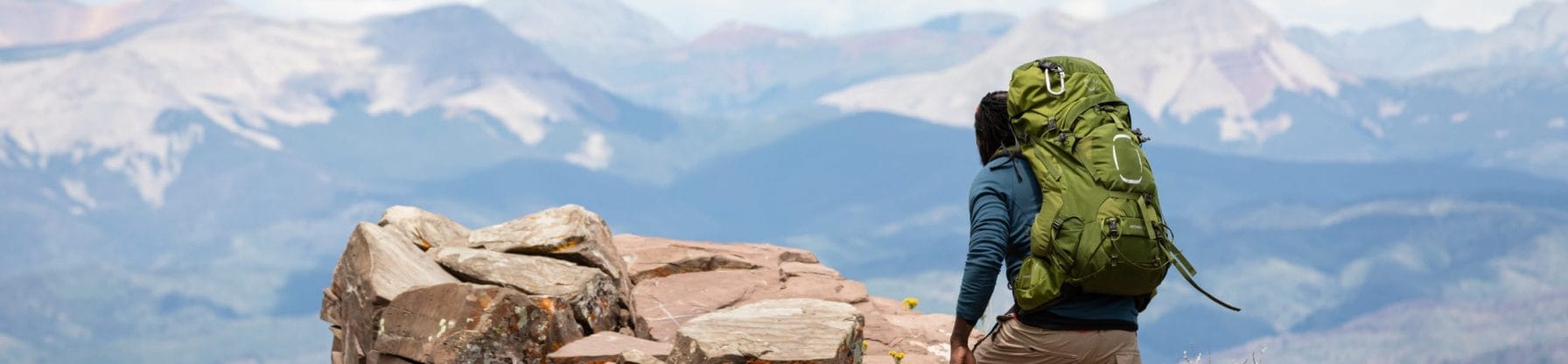 Man som bär bekväm Osprey ryggsäck på berg.