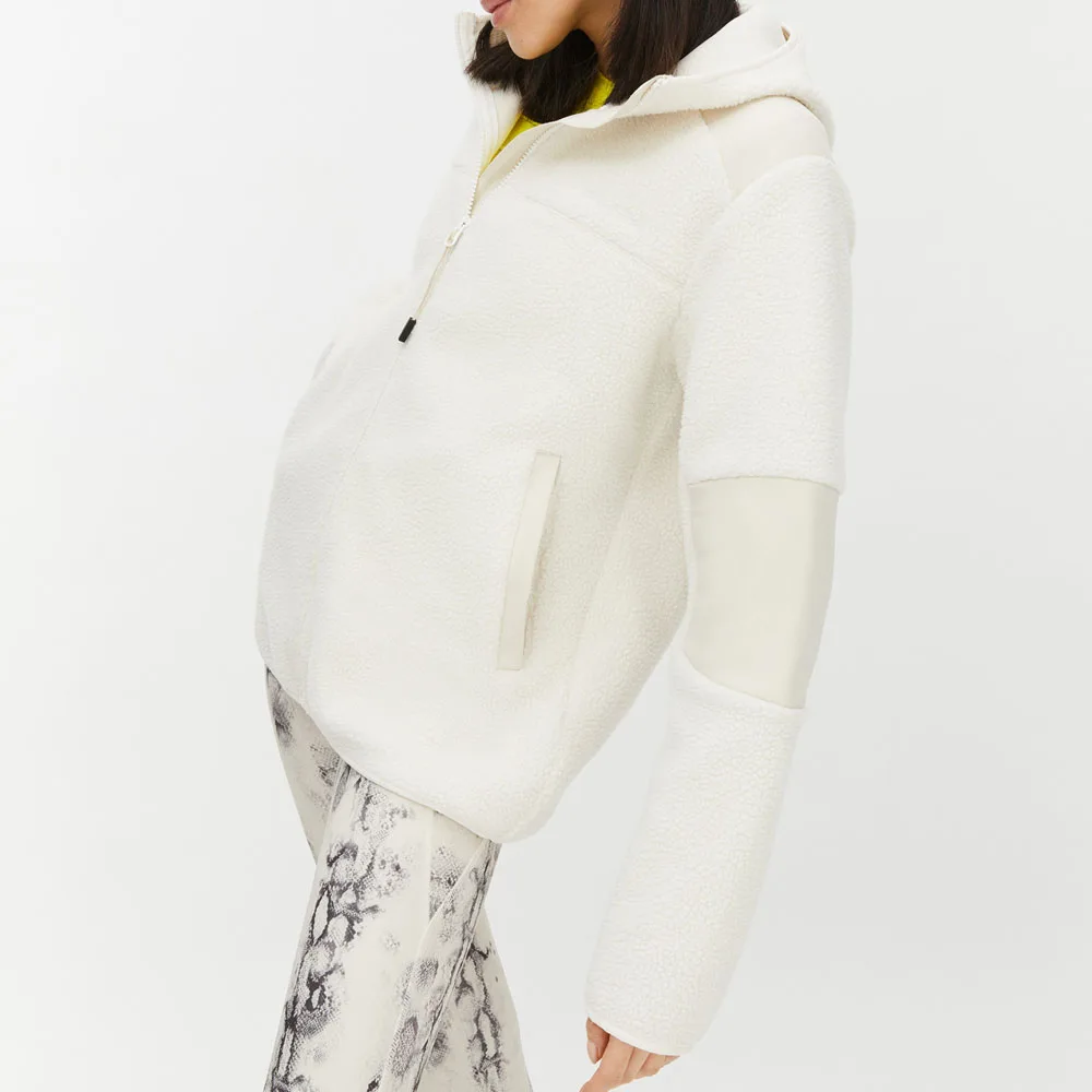 Röhnisch Wazzi Pile Hoodie, på en brunhårig modell som står åt sidan