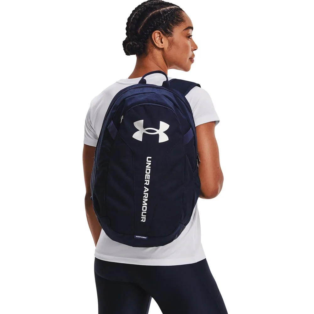 en modell bär en Under Armour Hustle Lite vardagsryggsäck (unisex)
