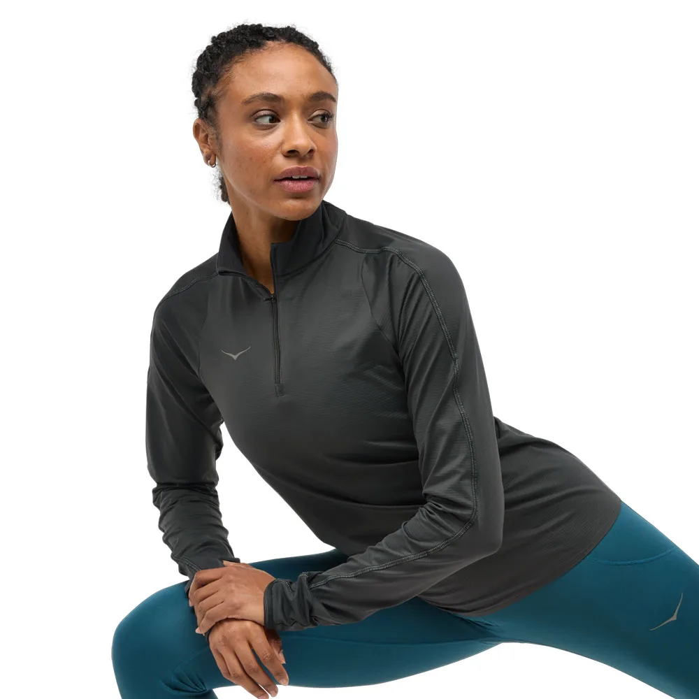 en modell bär en svart Hoka Glidetech Quarter Zip träningströja (dam)