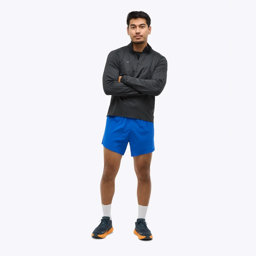 en modell bär en Hoka Glidetech Quarter Zip träningströja (herr)