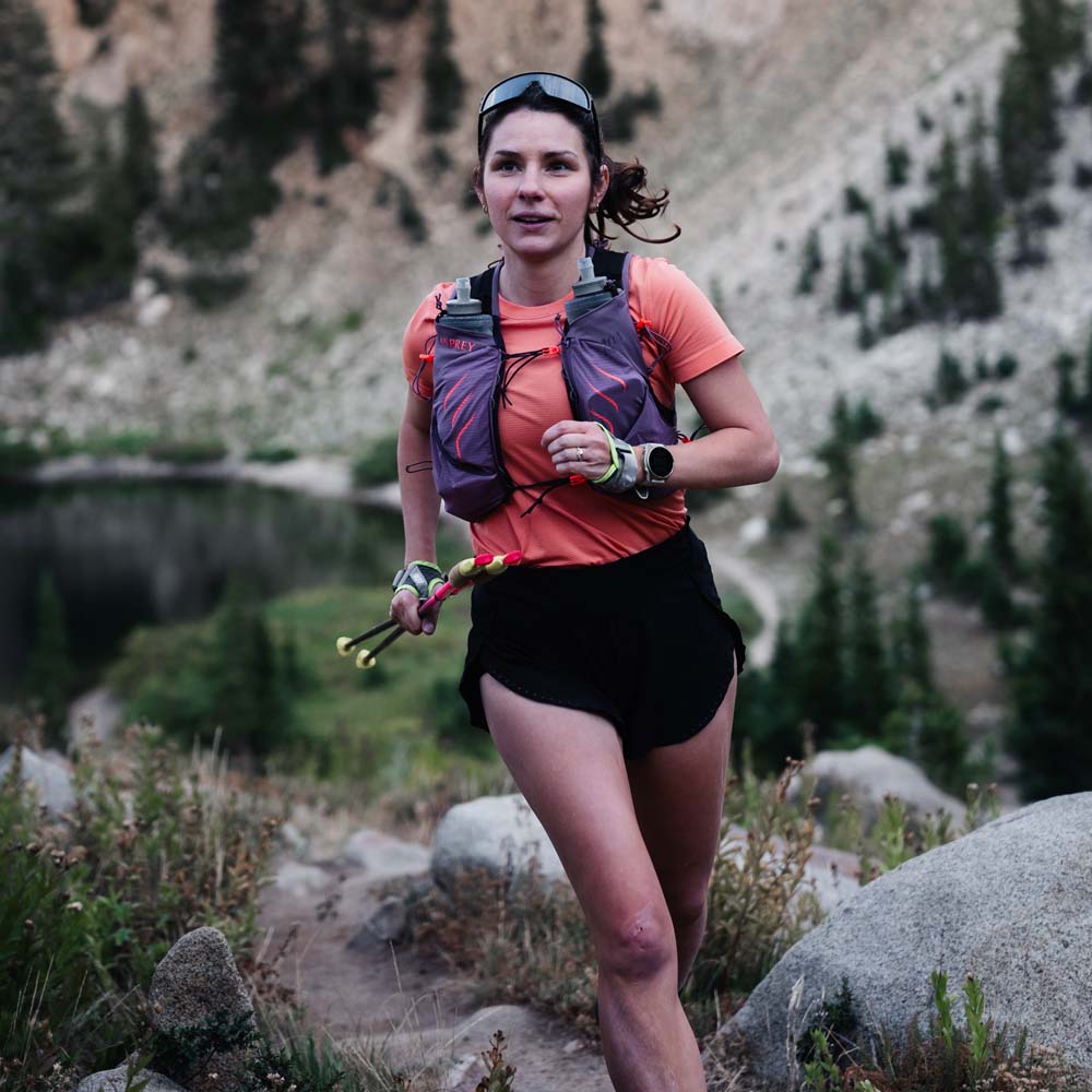 en kvinna springer med Osprey Dyna Pro 10 löparväst (dam)