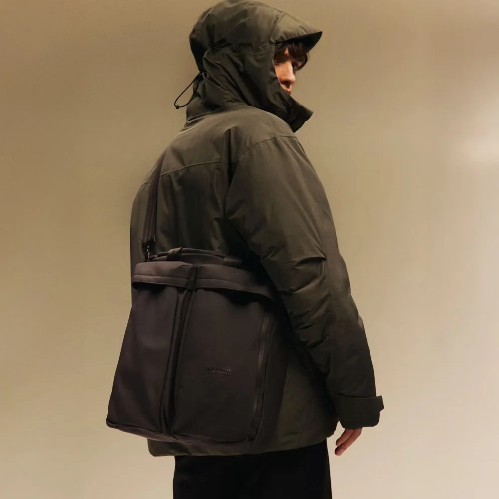 en modell bär en Tretorn Wings Shoulder Tote väska (unisex)på axeln