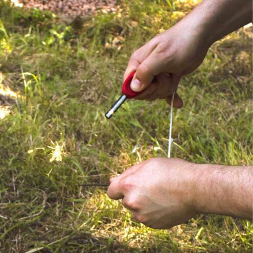 En person använder Eldstål med kompass för att göra gnistor.