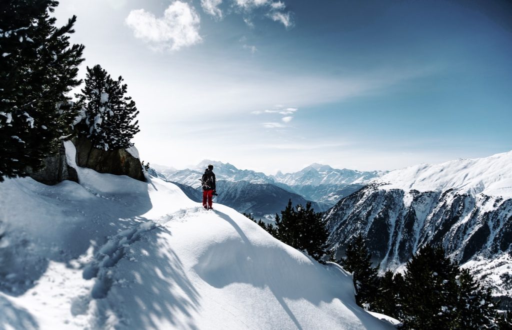 Person uppskattar snötäckta berg och fjällandskap på sin vintervandring.