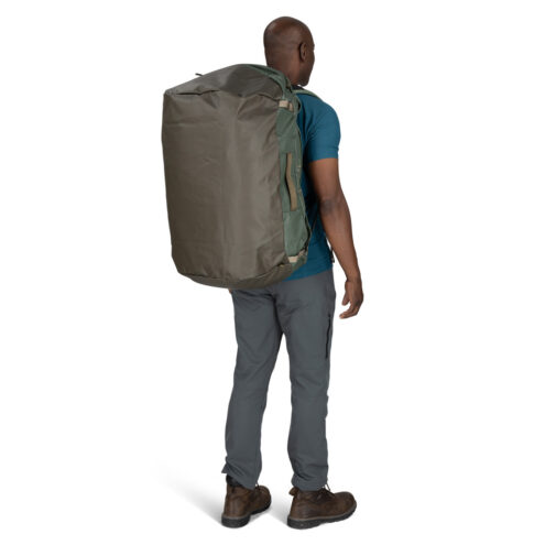 en man bär Osprey Transporter Duffel 95L (unisex) på ryggen