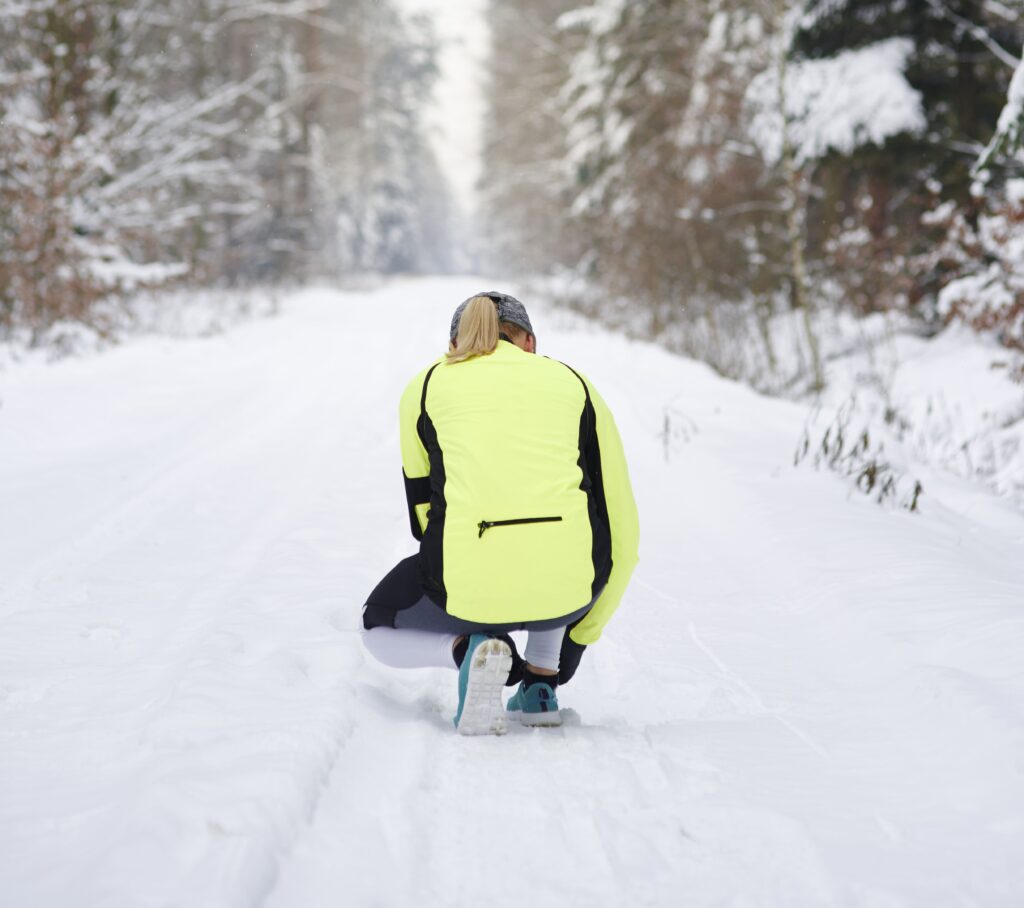 Tjej som knyter skorna i ett löpspår under vintern